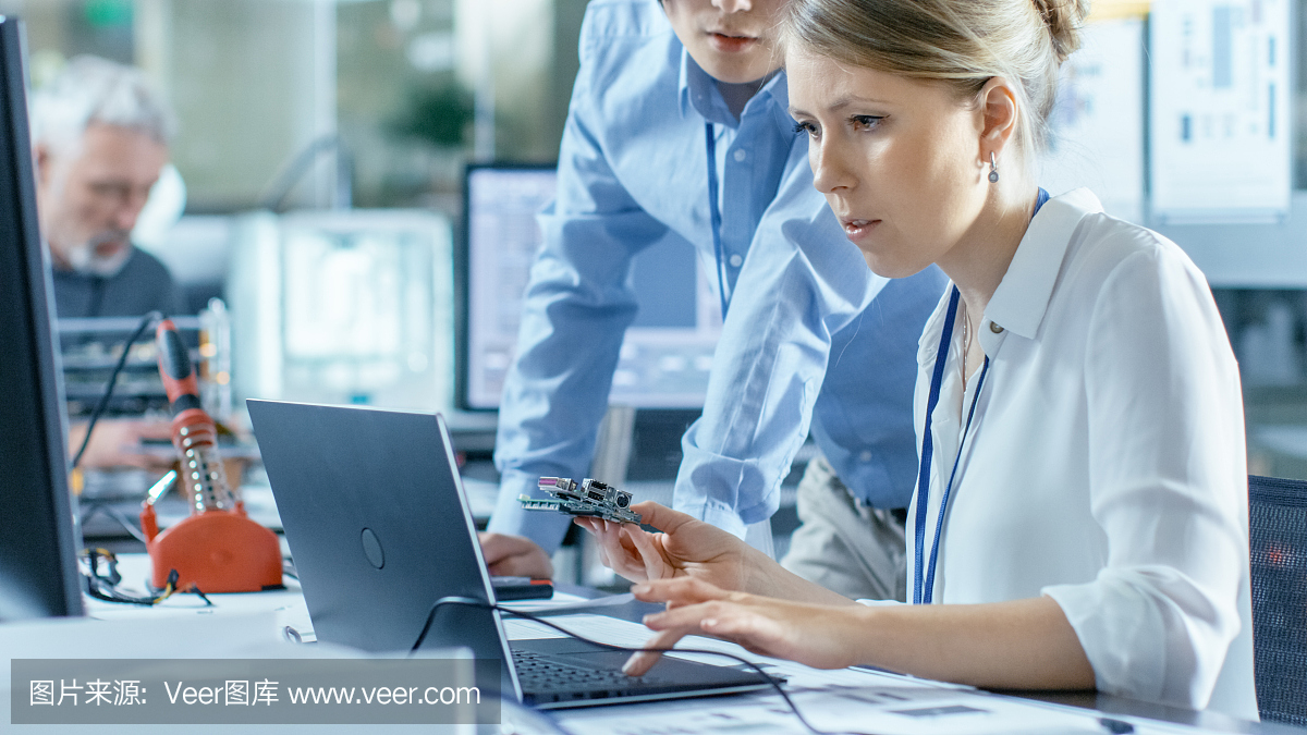 女計算機科學家將電路板連接到她的筆記本電腦并開始編程。她在先進技術實驗室工作。